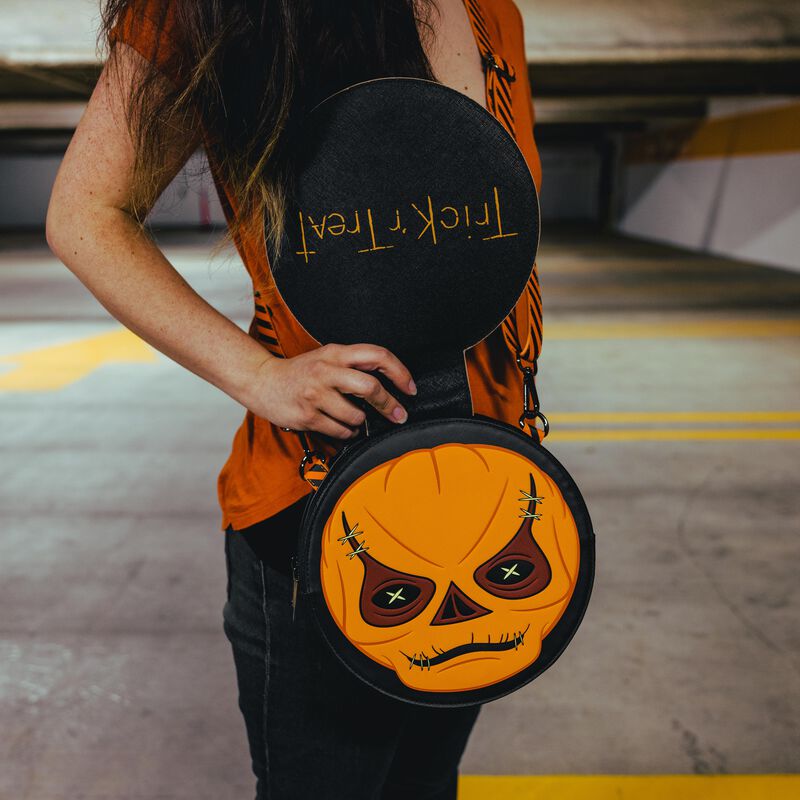 Image of woman wearing the Trick 'r Treat Crossbody Bag with the front flap open to reveal Sam's pumpkin face beneath his costume